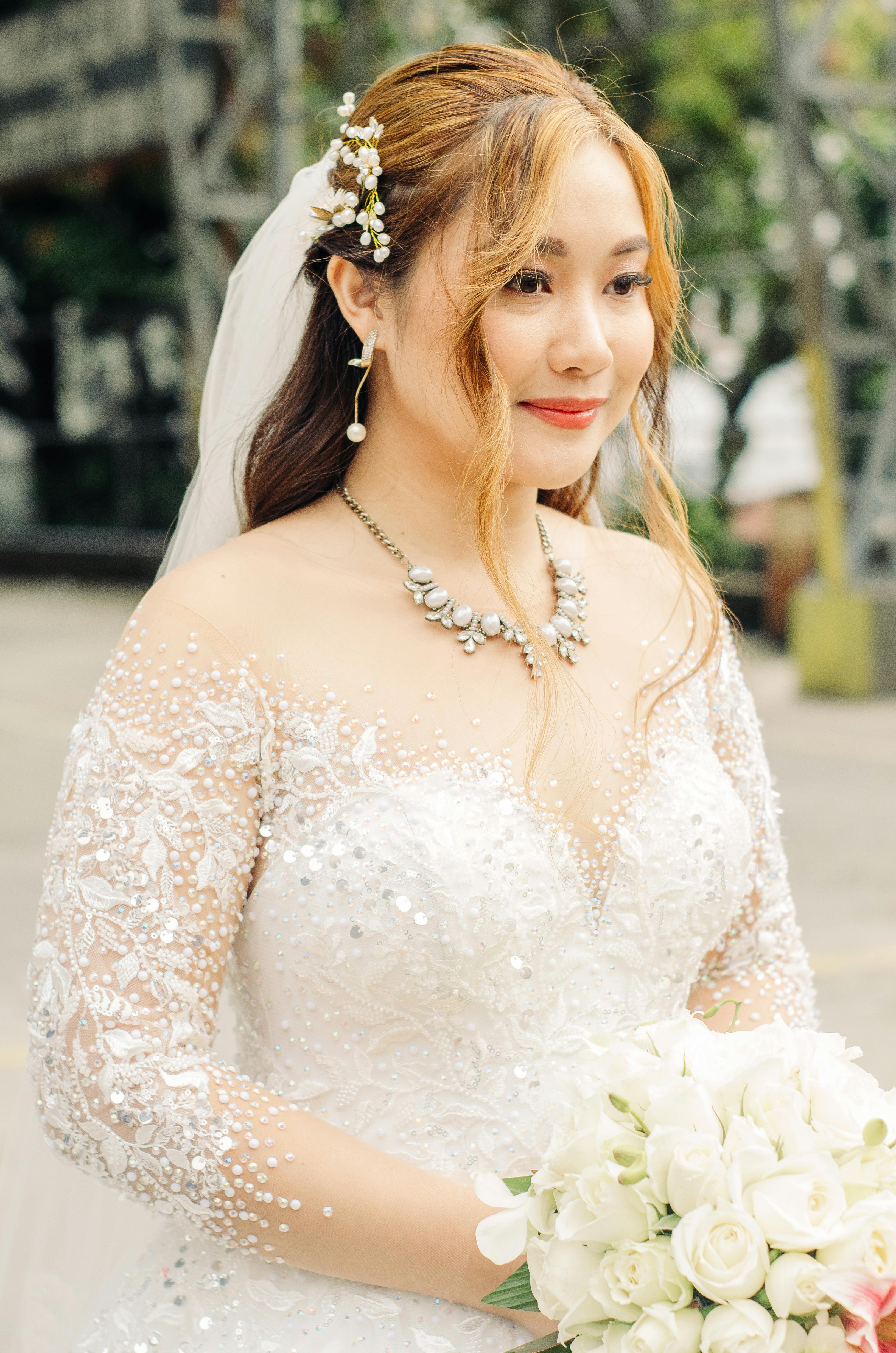 Bride in a lace gown holding white roses, showcasing elegance and beauty.