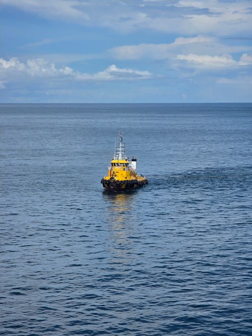Free A yellow tugboat sails across a calm ocean under a cloudy sky in Indonesia. Stock Photo