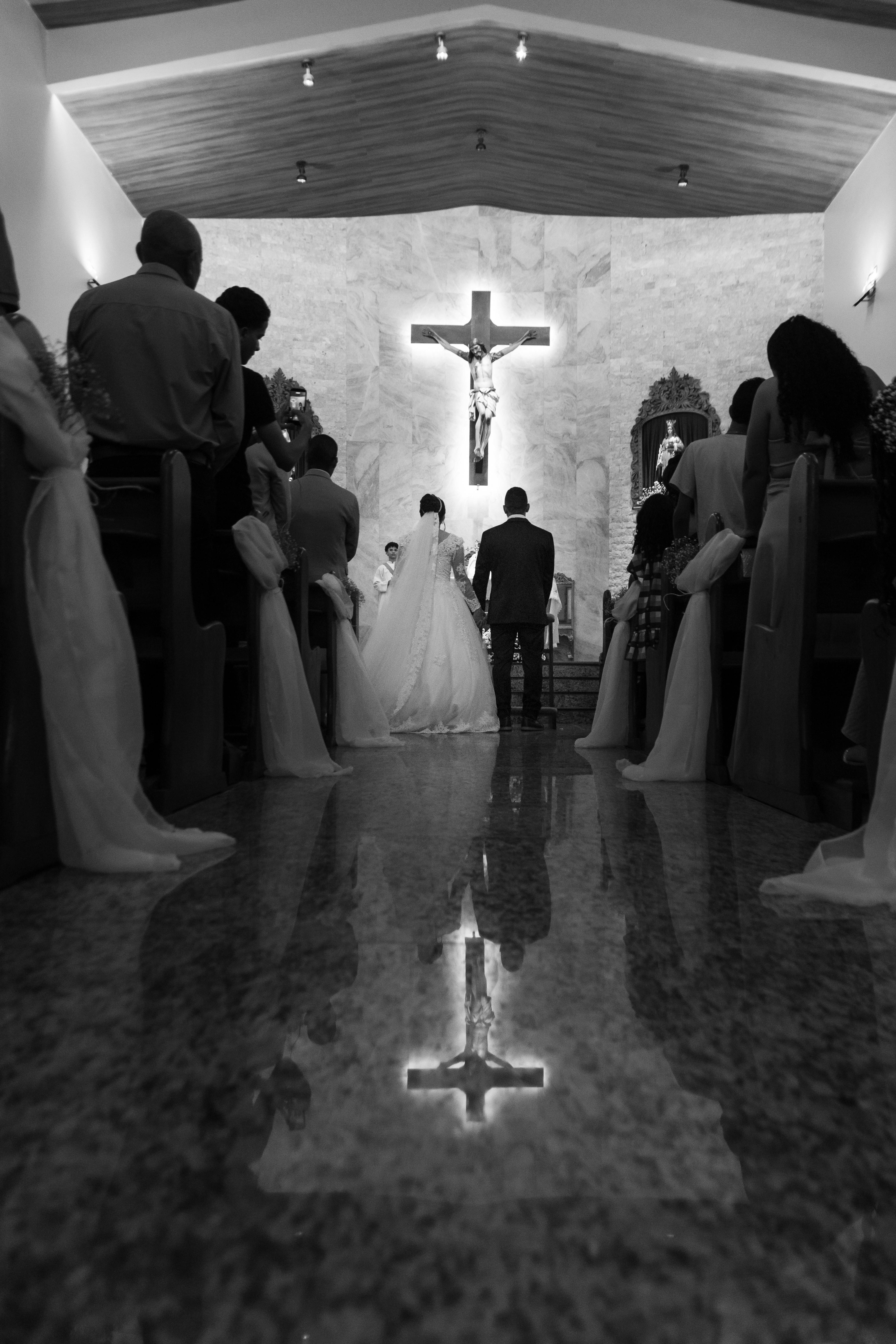 A couple getting married in a church with guests and a crucifix.