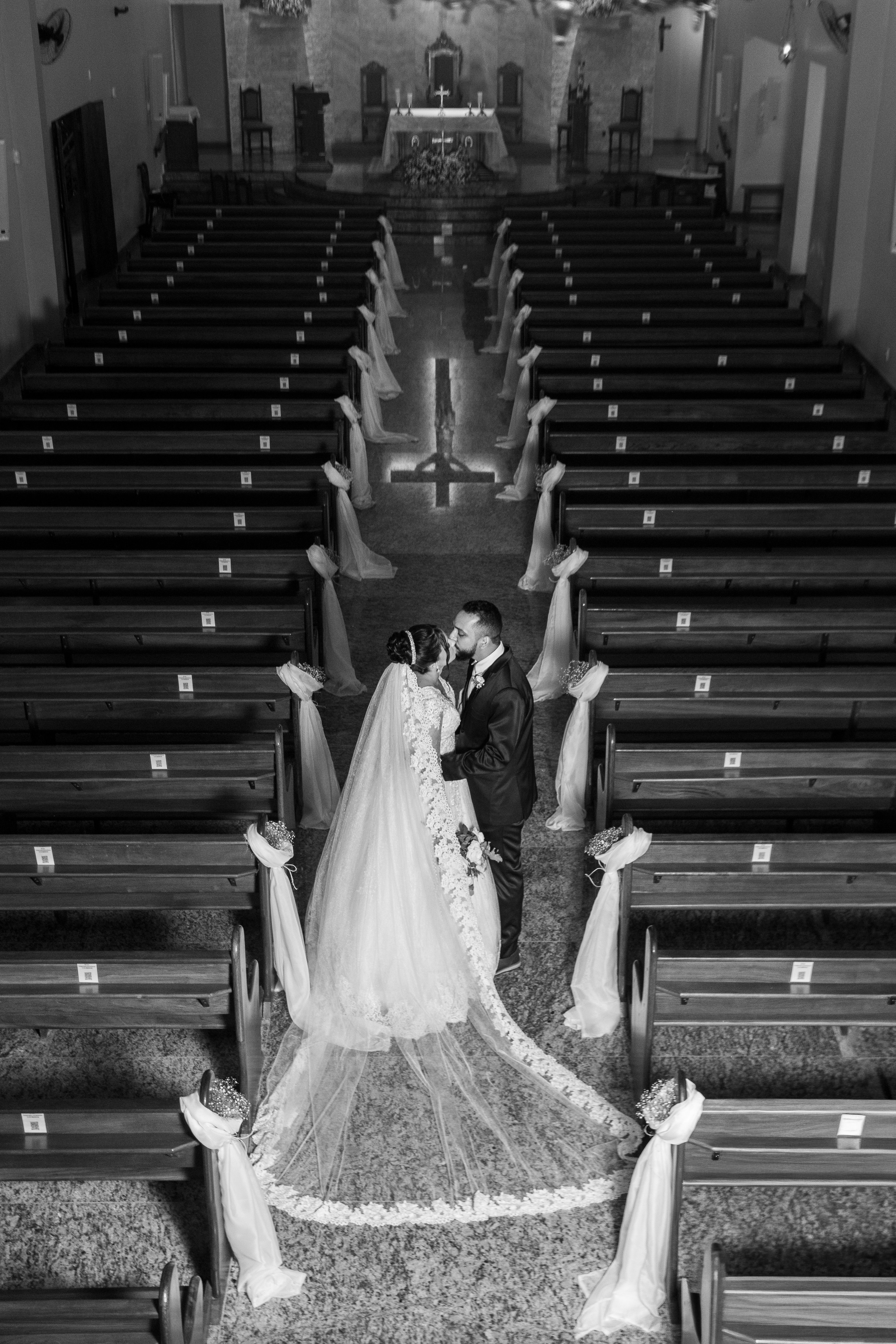 Elegant black and white photo of a couple kissing in a church wedding ceremony.