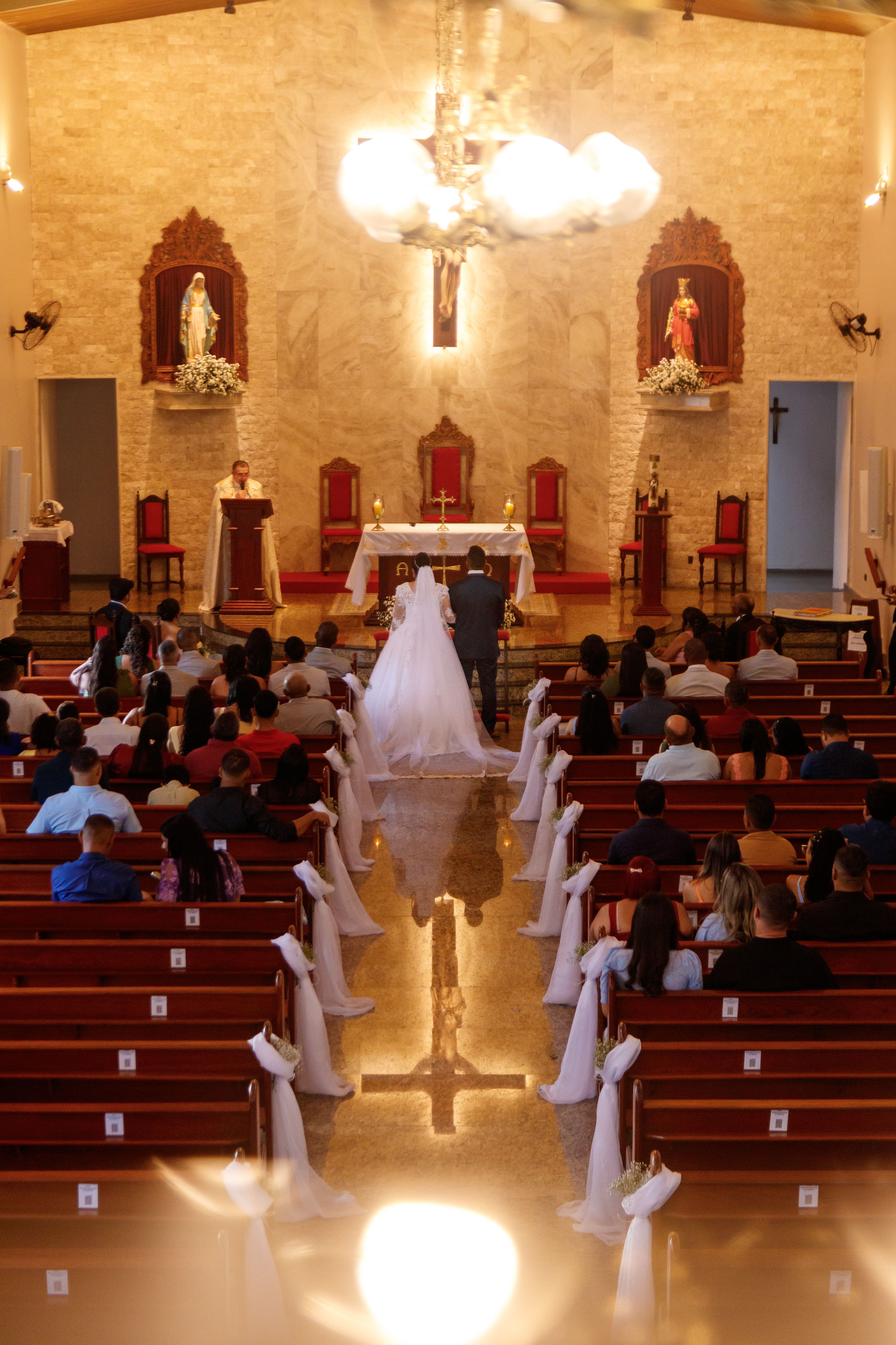 An elegant wedding ceremony in a beautifully decorated church with attendees seated in pews.