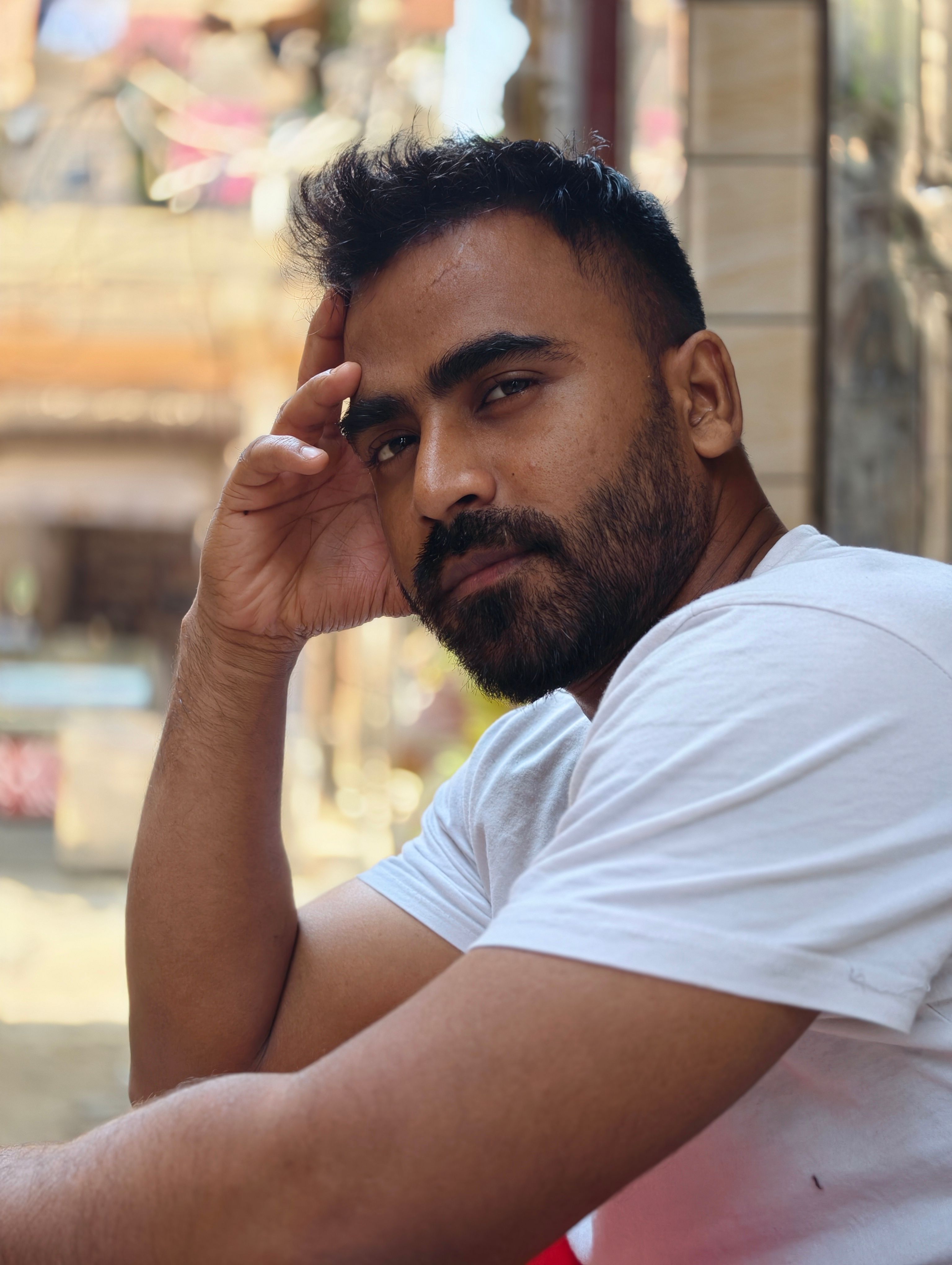 A man in a white shirt poses thoughtfully outdoors, capturing a moment of contemplation.