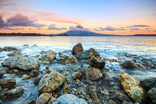 бесплатная Коричневые и серые скалы на берегу моря во время заката Стоковое фото