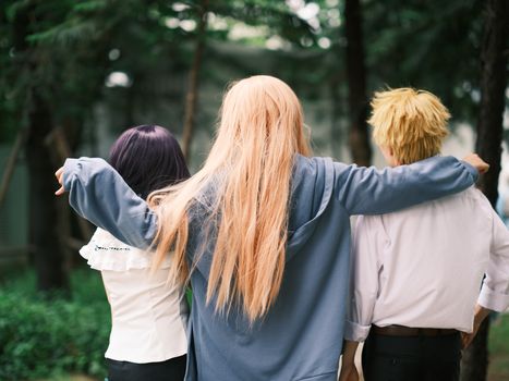 Group of anime cosplay enthusiasts embracing outdoors in vibrant costumes.