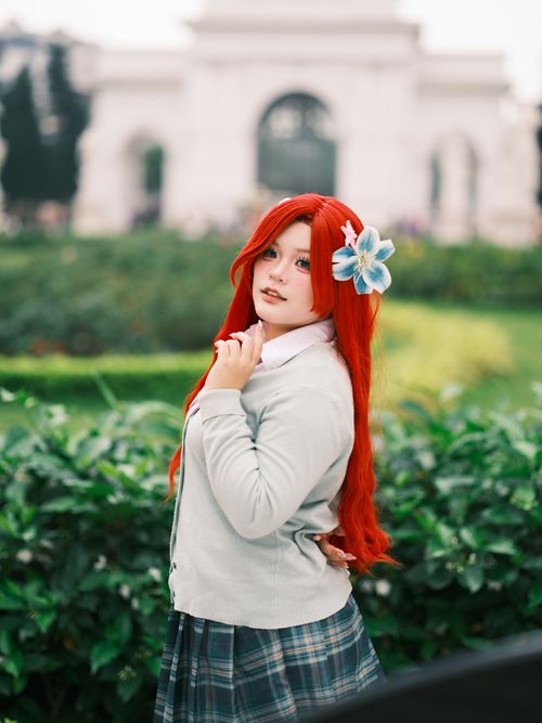 Free A vibrant cosplay portrait featuring a character with red hair and a blue flower outdoors in Việt Nam. Stock Photo
