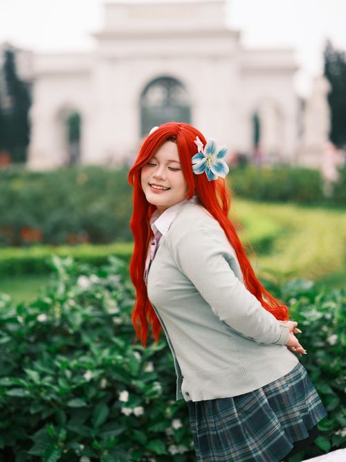 Free Cheerful woman in cosplay with long red hair posing in a lush green garden. Stock Photo