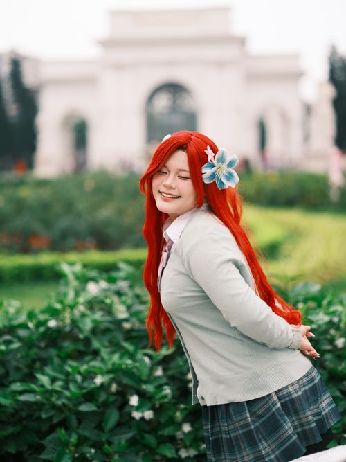 Free A young woman in cosplay poses joyfully in a lush garden with an iconic landmark in the background. Stock Photo