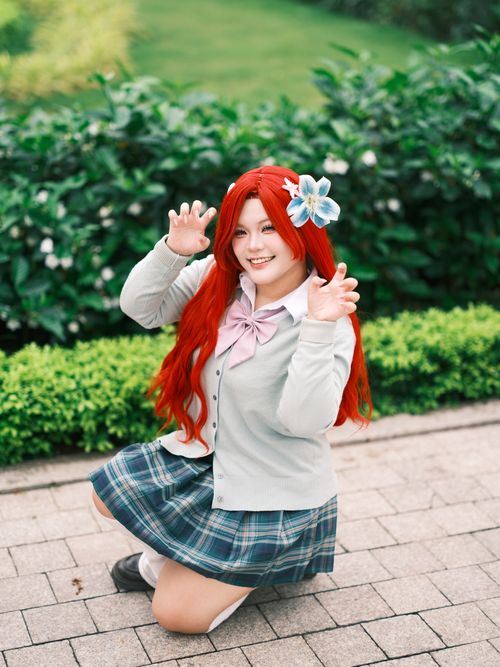 Free Cosplay enthusiast poses with vibrant red hair in a lush green outdoor setting. Stock Photo