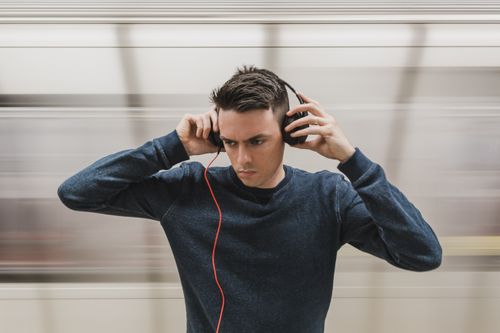 Free Focused young man with headphones in a moving subway station, showcasing modern lifestyle and technology. Stock Photo