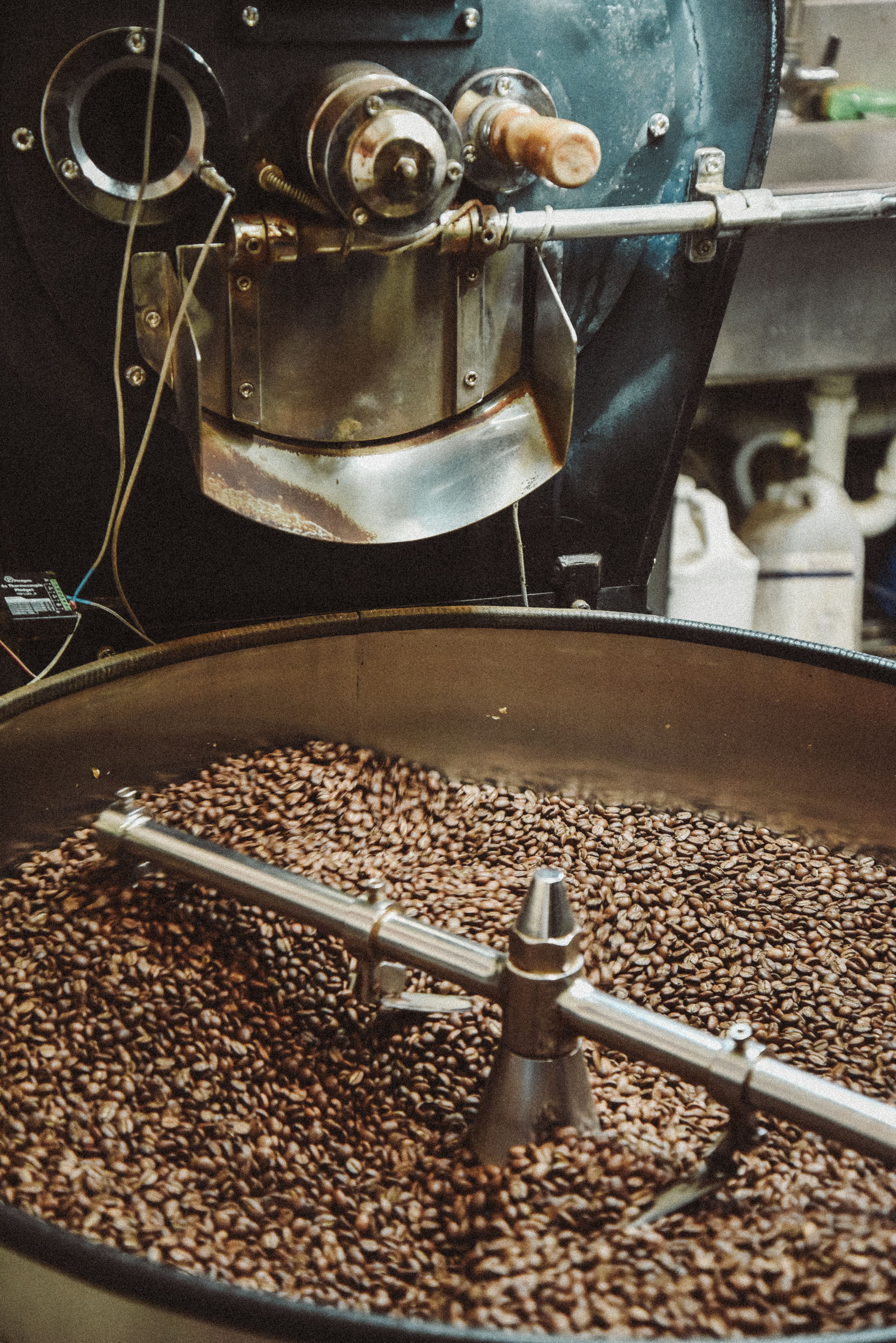 A detailed view of an industrial coffee roaster processing fresh coffee beans, highlighting the machinery and rich texture.
