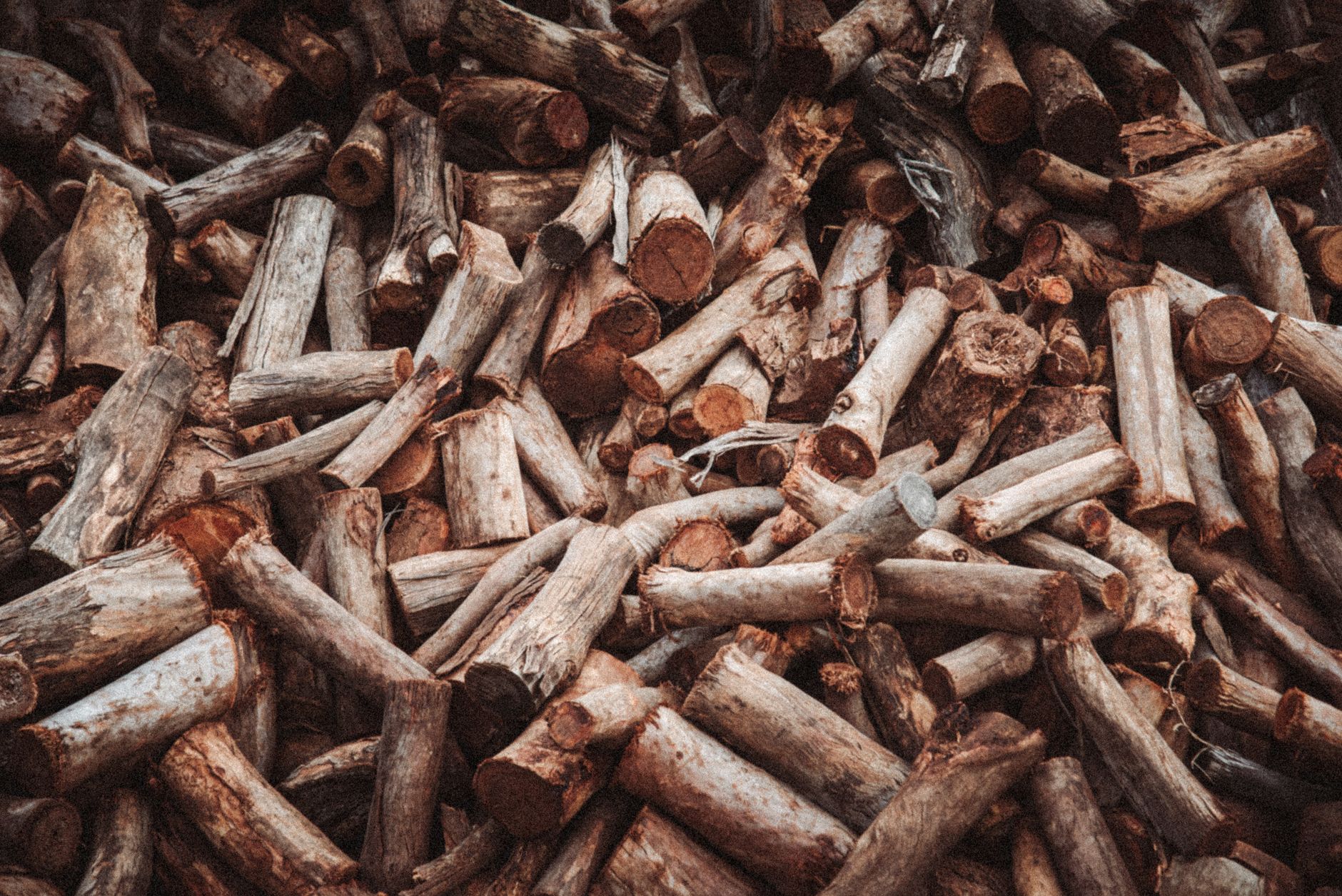 A large pile of cut firewood logs with a rustic texture, ideal for winter heating.