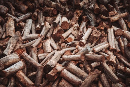 A large pile of cut firewood logs with a rustic texture, ideal for winter heating.