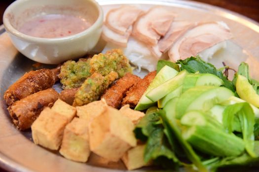 Delicious assortment of Asian vegetarian snacks with fresh greens on a silver platter.