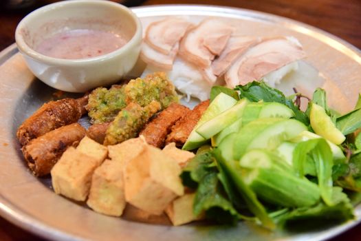 A close-up of a traditional Asian platter featuring assorted meats, vegetables, and dipping sauce.