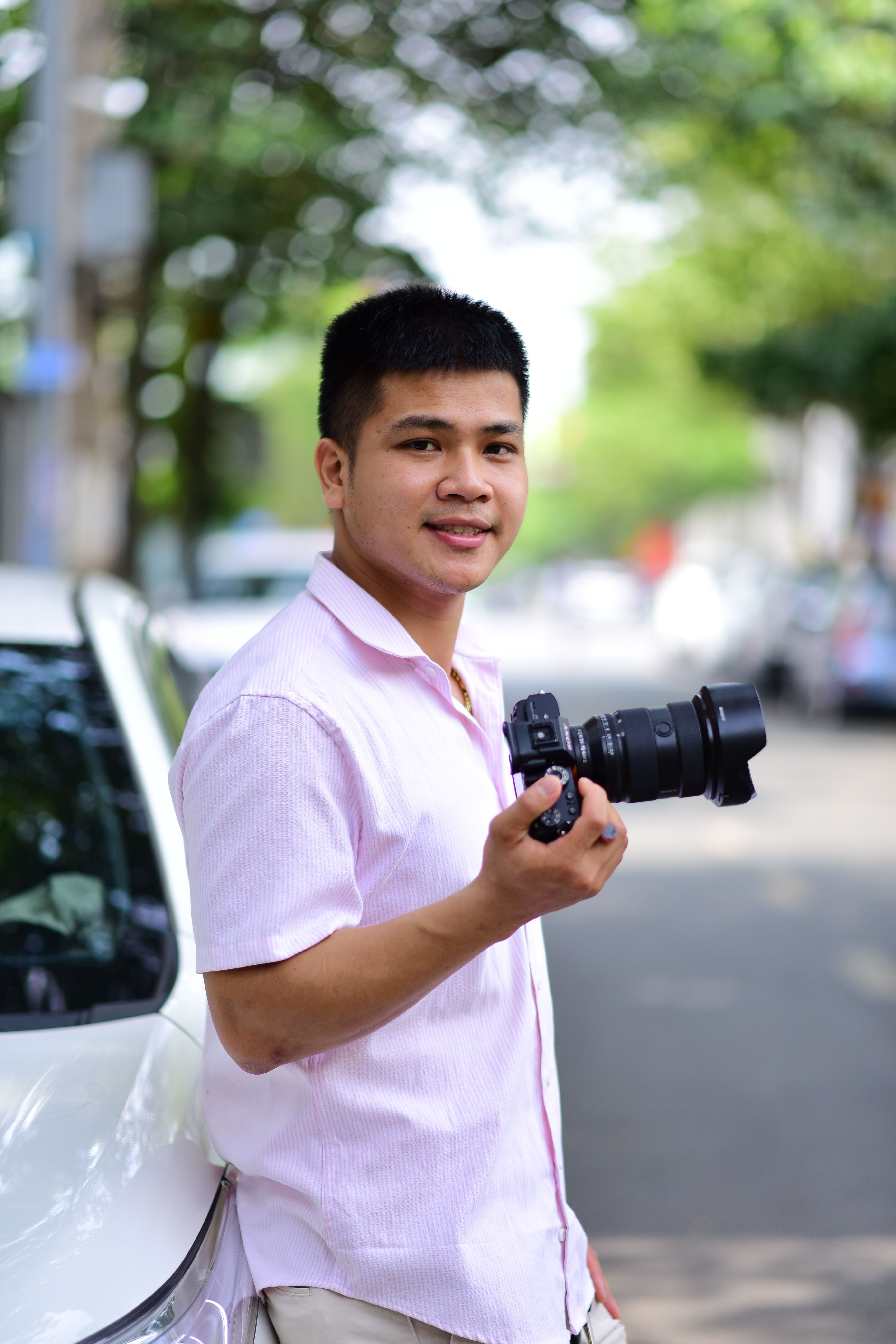 Smiling photographer holding a camera on an urban street.