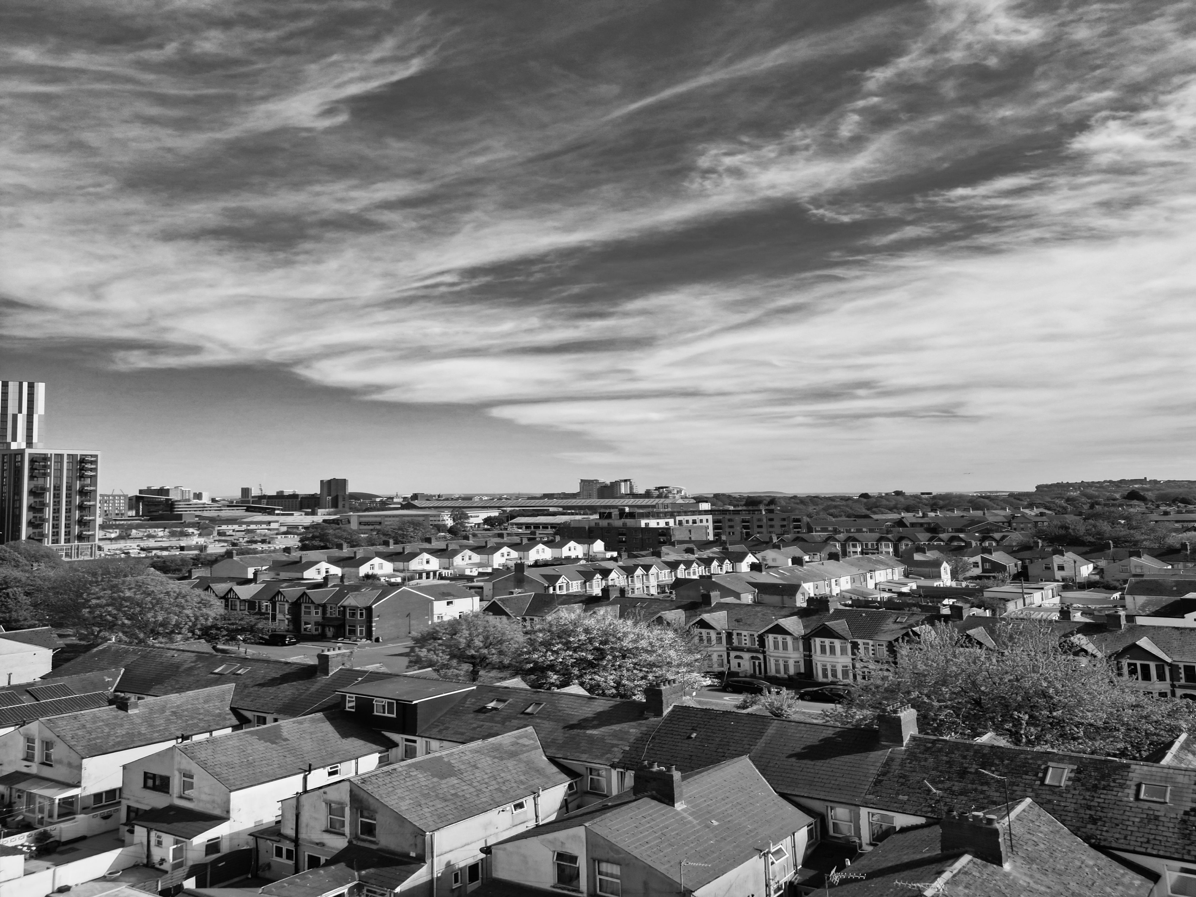 A monochrome aerial photograph capturing the urban skyline of Cardiff, UK under a dramatic sky.
