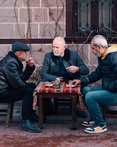 Free Three men socializing over tea at an outdoor cafe in Ankara, Türkiye. Stock Photo