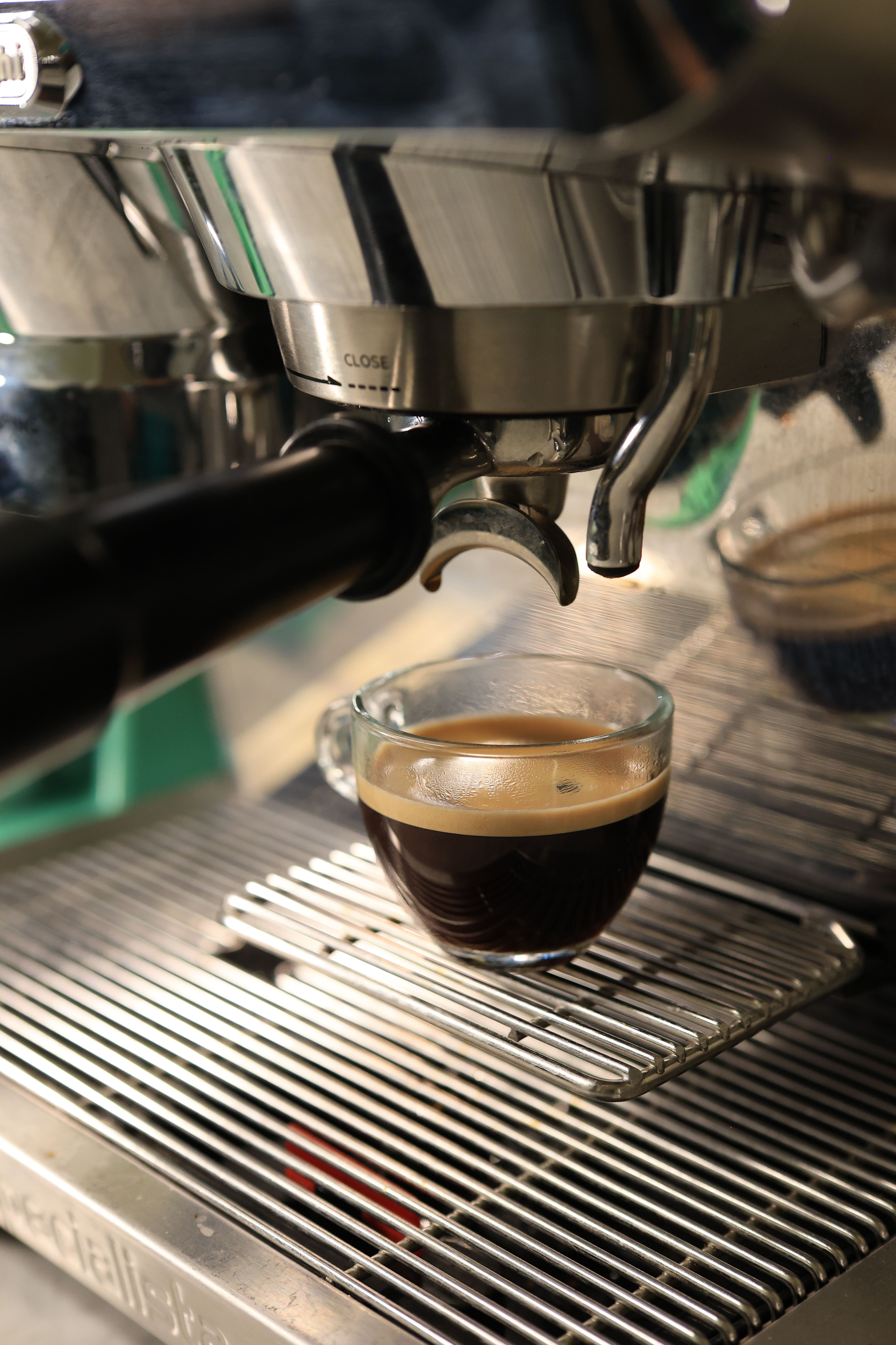 Close-up of espresso brewing under a professional machine, showing rich crema.
