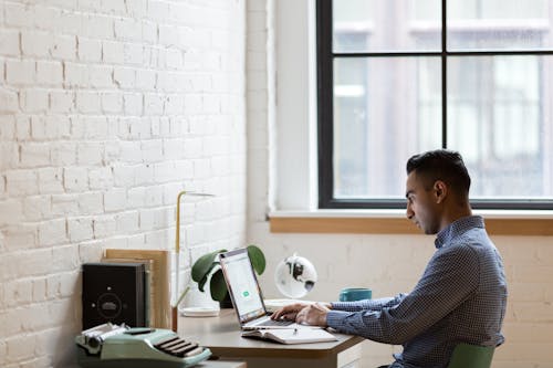 Free Man Sitting on Green Chair While Using Laptop Stock Photo