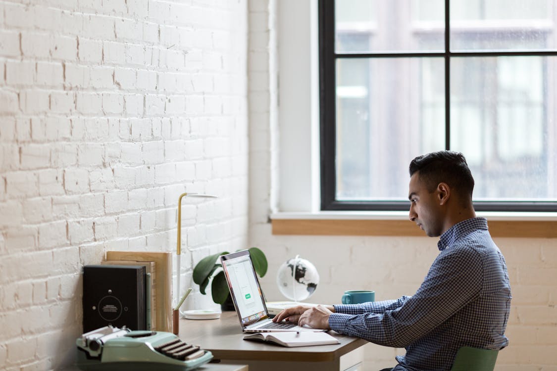 Free Man Sitting on Green Chair While Using Laptop Stock Photo