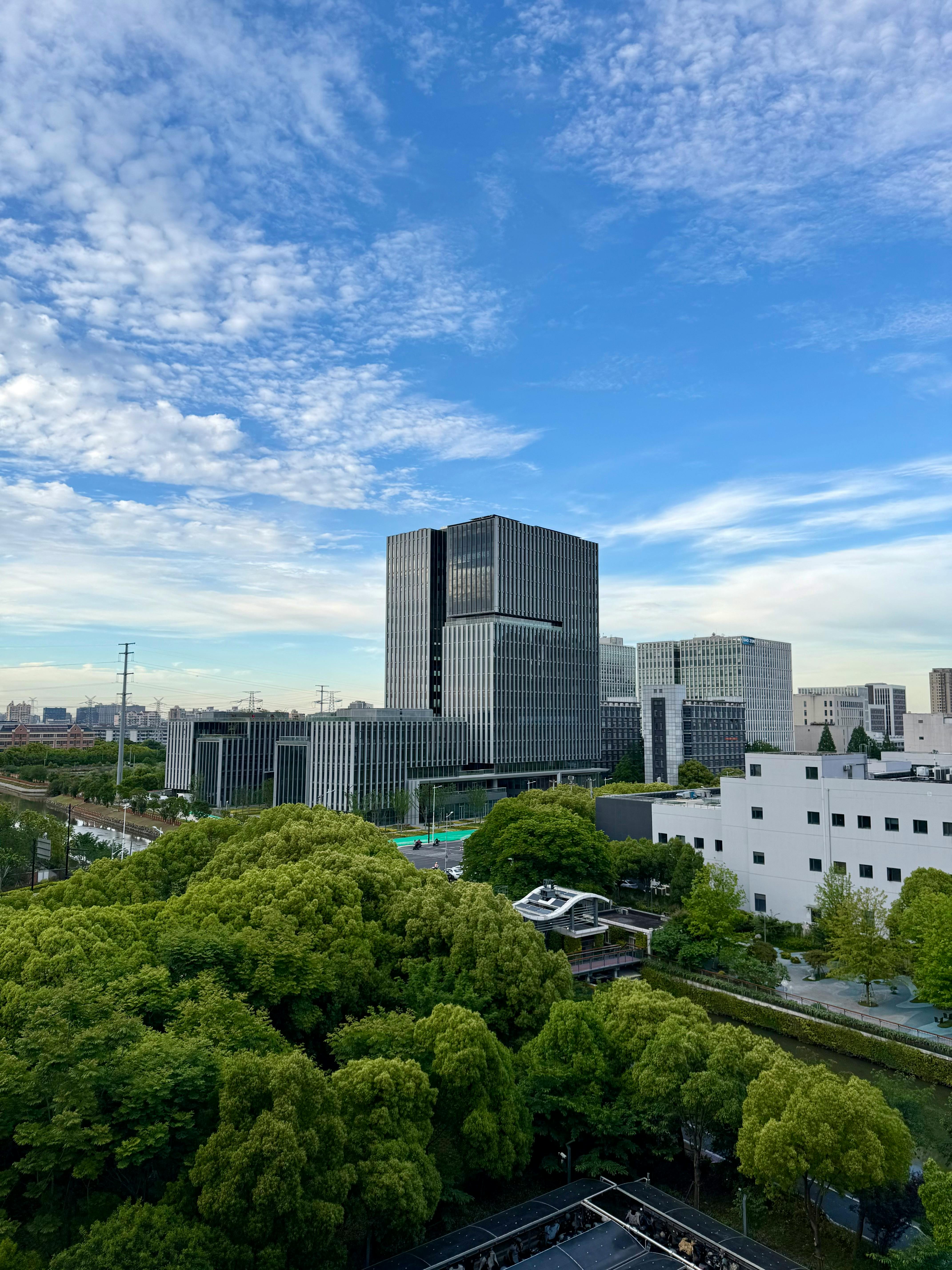 View of Shanghai's contemporary buildings surrounded by lush green trees under a bright sky.