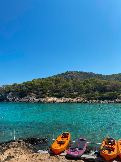 Free Kayaks rest by the crystal-clear waters and lush greenery of Megalochori, Greece, perfect for adventure seekers. Stock Photo