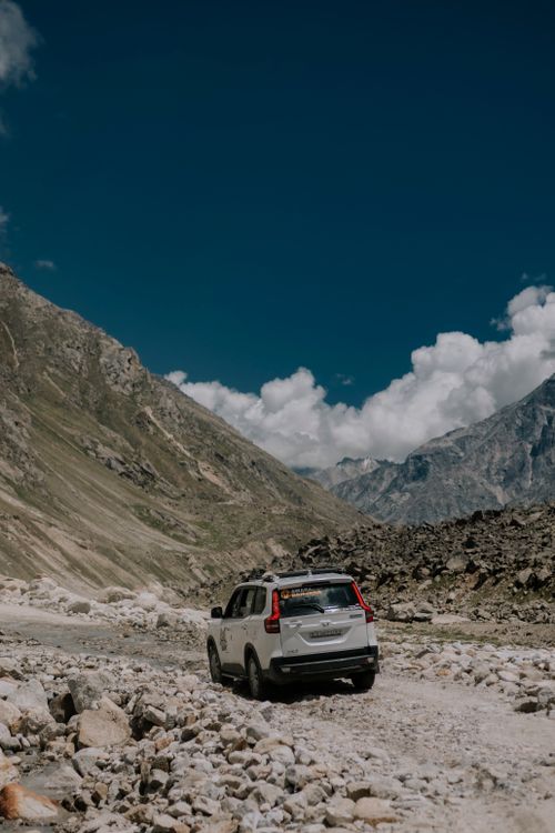 Free A white SUV traverses the rugged landscape of Spiti Valley under a clear blue sky, showcasing adventure and travel. Stock Photo