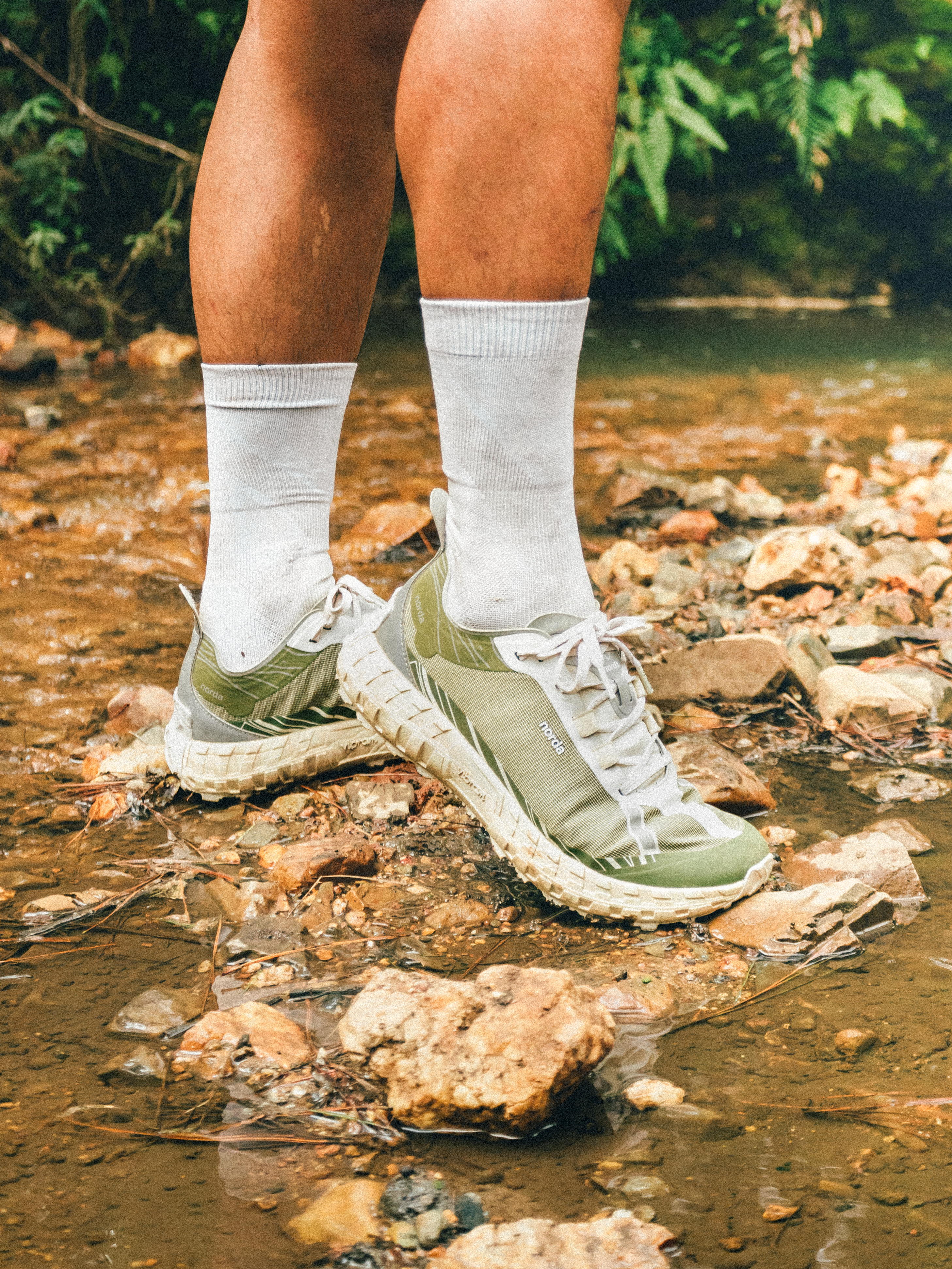 Close-up of trekking shoes crossing a rocky stream in Lâm Đồng, Vietnam. Perfect for adventure and travel themes.