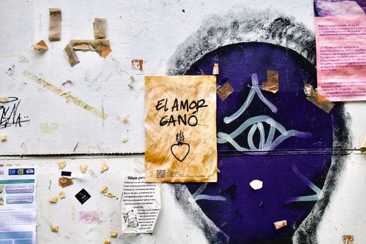 A vibrant street art wall in Mexico City featuring the message 'El Amor Ganó' amidst colorful graffiti and posters.