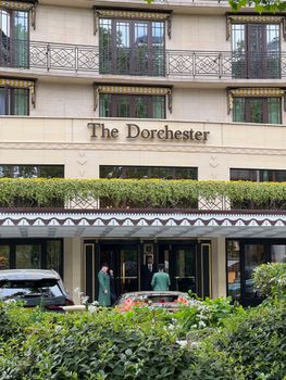 Front view of The Dorchester Hotel in London, featuring classic architecture and lush greenery.