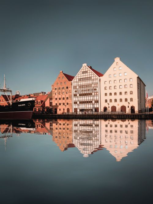 Free Charming reflection of historic buildings along the Gdańsk waterfront at sunrise. Stock Photo