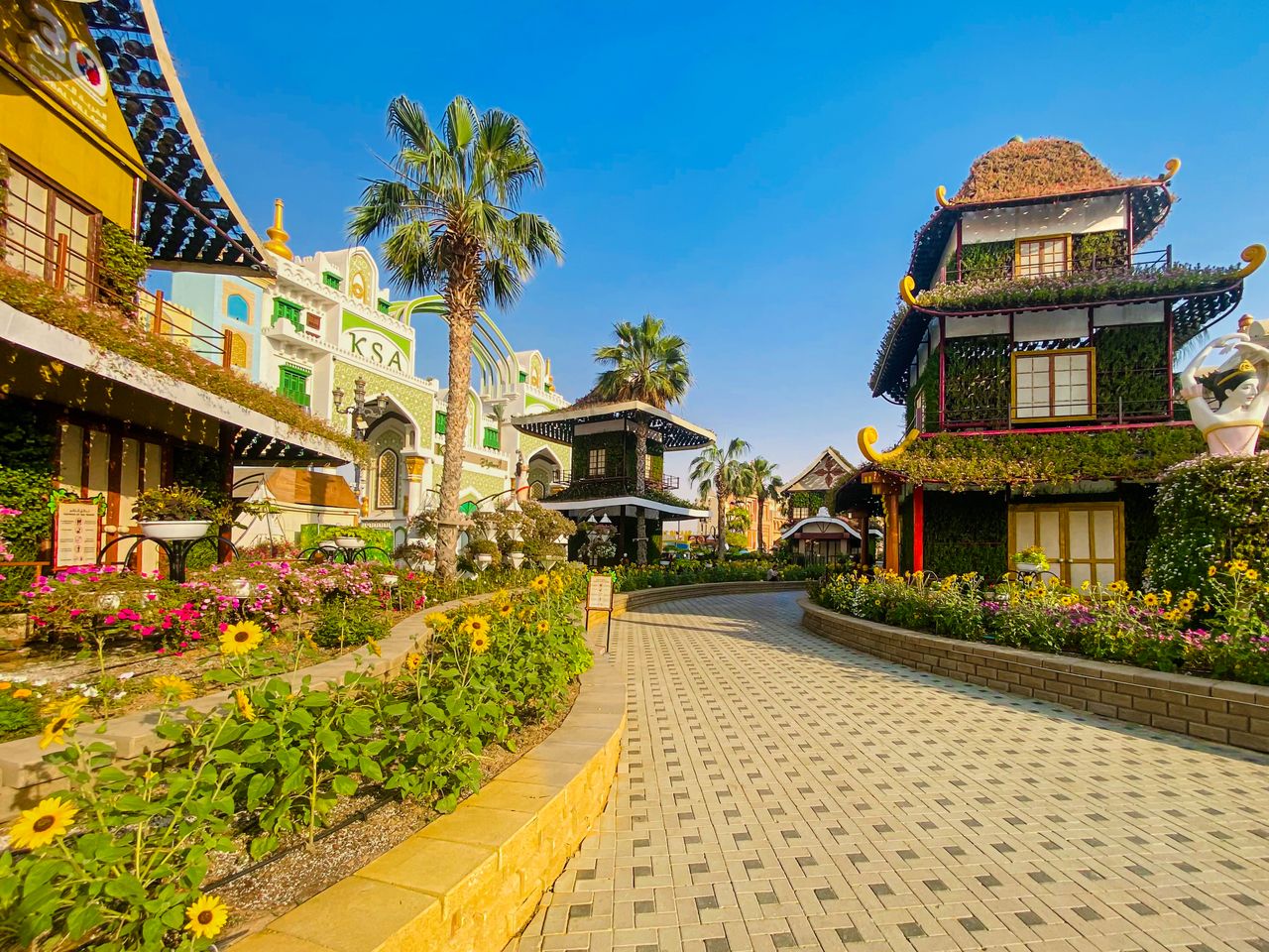 Flower beds and a pagoda-style building along a path at Global Village
