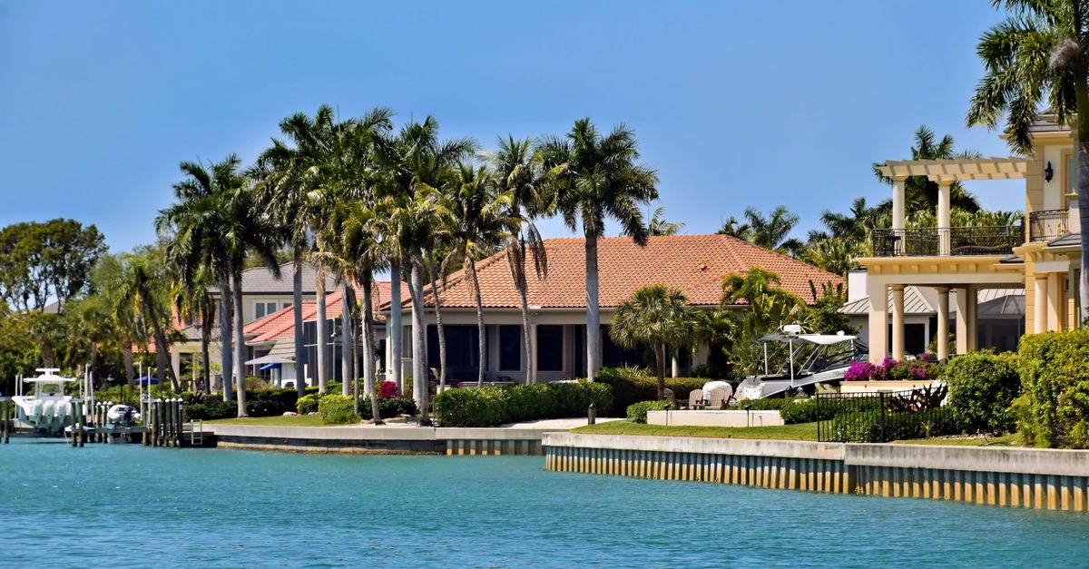 Scenic view of luxury waterfront villas and palm trees under a clear blue sky.