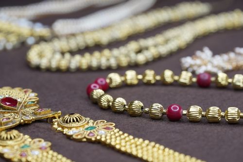 Free Close-up of exquisite gold and ruby jewelry arranged on a rich brown fabric, highlighting intricate details. Stock Photo