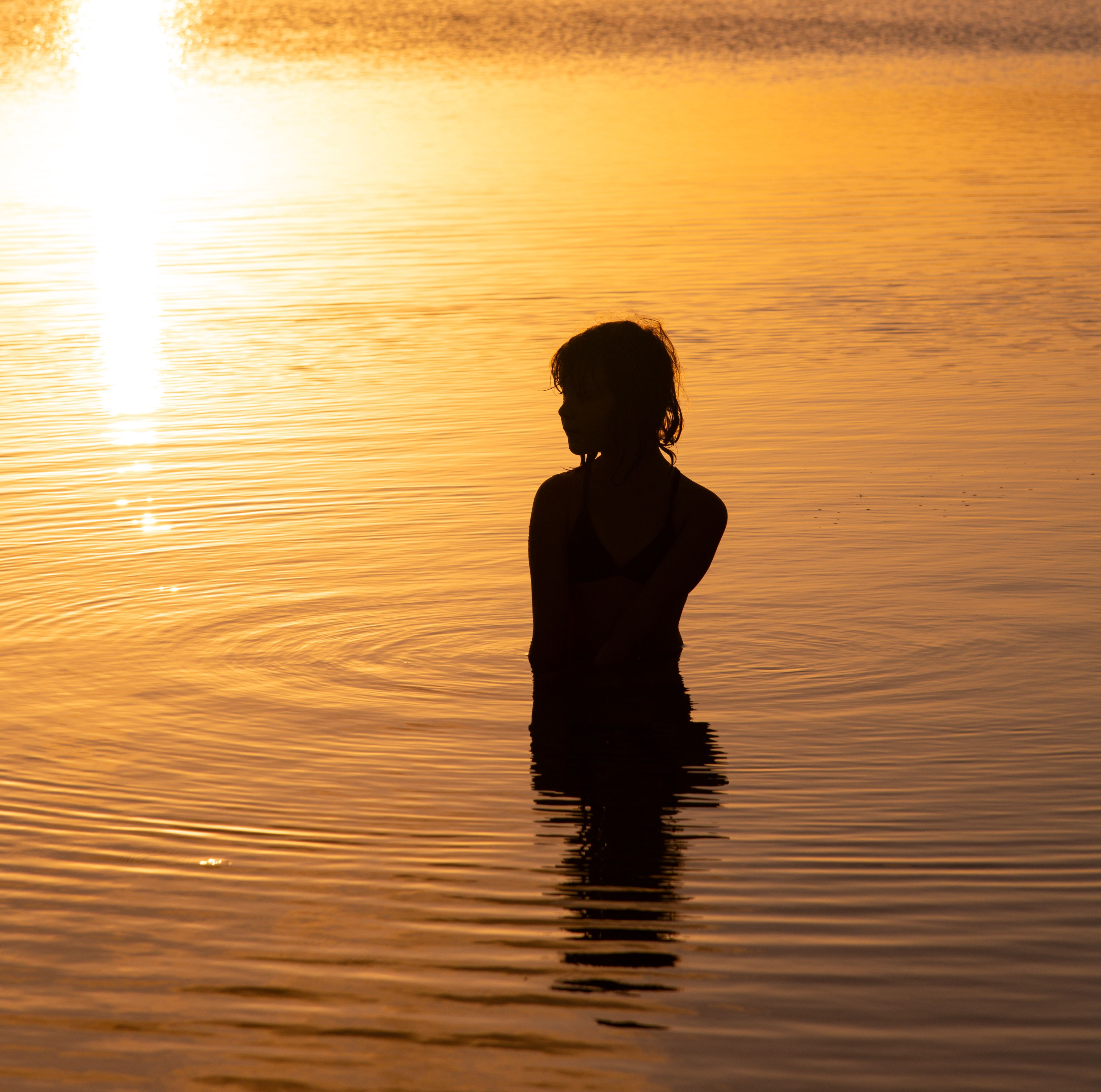 Silhouette of Person in Water at Sunset · Free Stock Photo