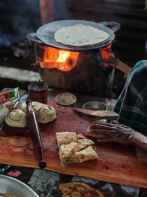 Free Artisan making flatbread on open fire with traditional tools, highlighting cultural culinary techniques. Stock Photo