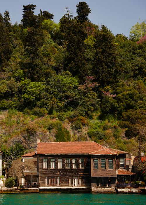 Free Charming historic house by the water against lush greenery in Istanbul, showcasing traditional architecture. Stock Photo