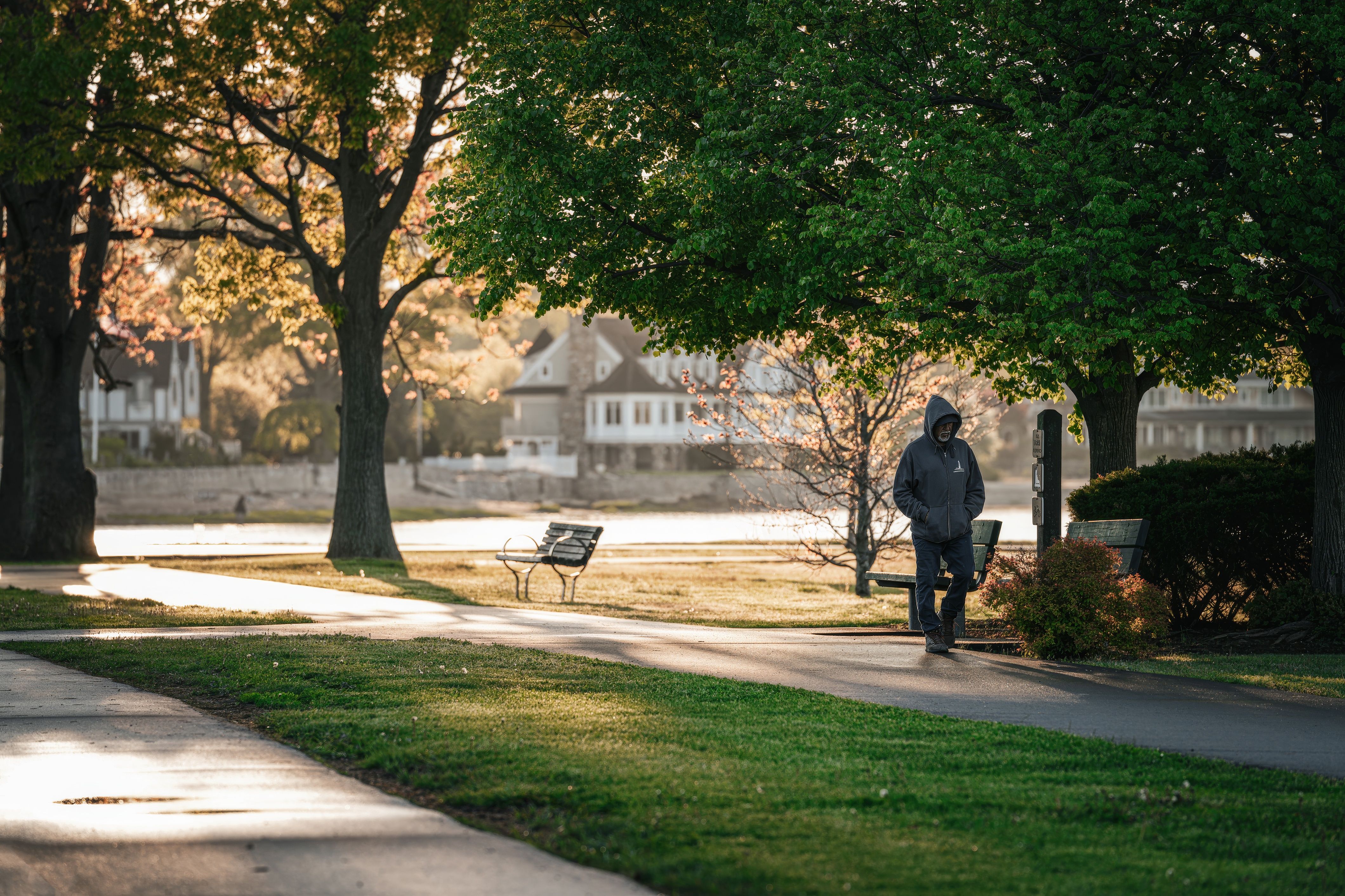 A person walking through a sunlit park during the morning