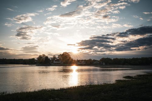 Free Peaceful sunset over a lake with beautiful reflections and houses in the background. Stock Photo