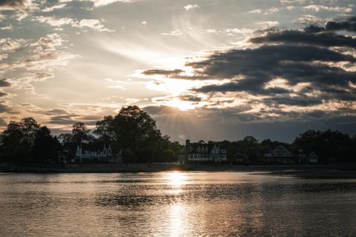 Free Peaceful evening scene of a lakeside sunset with striking clouds and silhouetted homes. Stock Photo