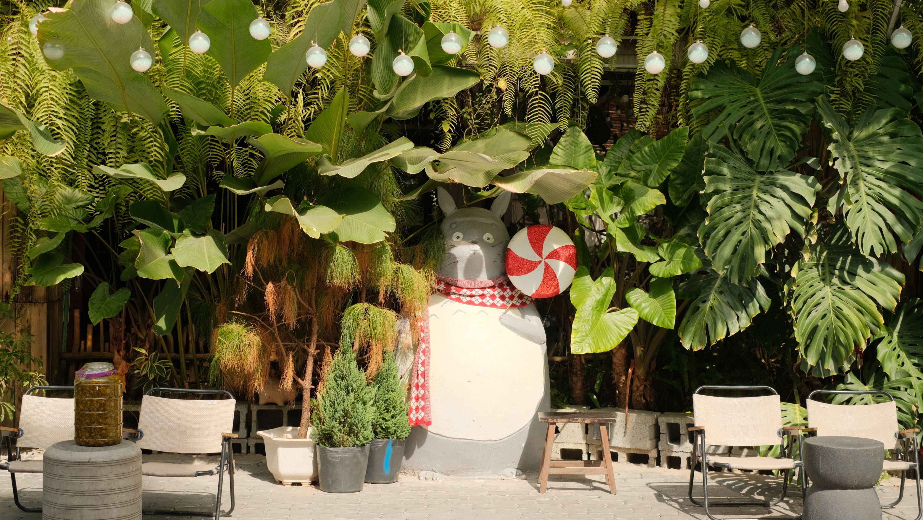 Whimsical outdoor garden scene with lush greenery and a cartoon figure sculpture.