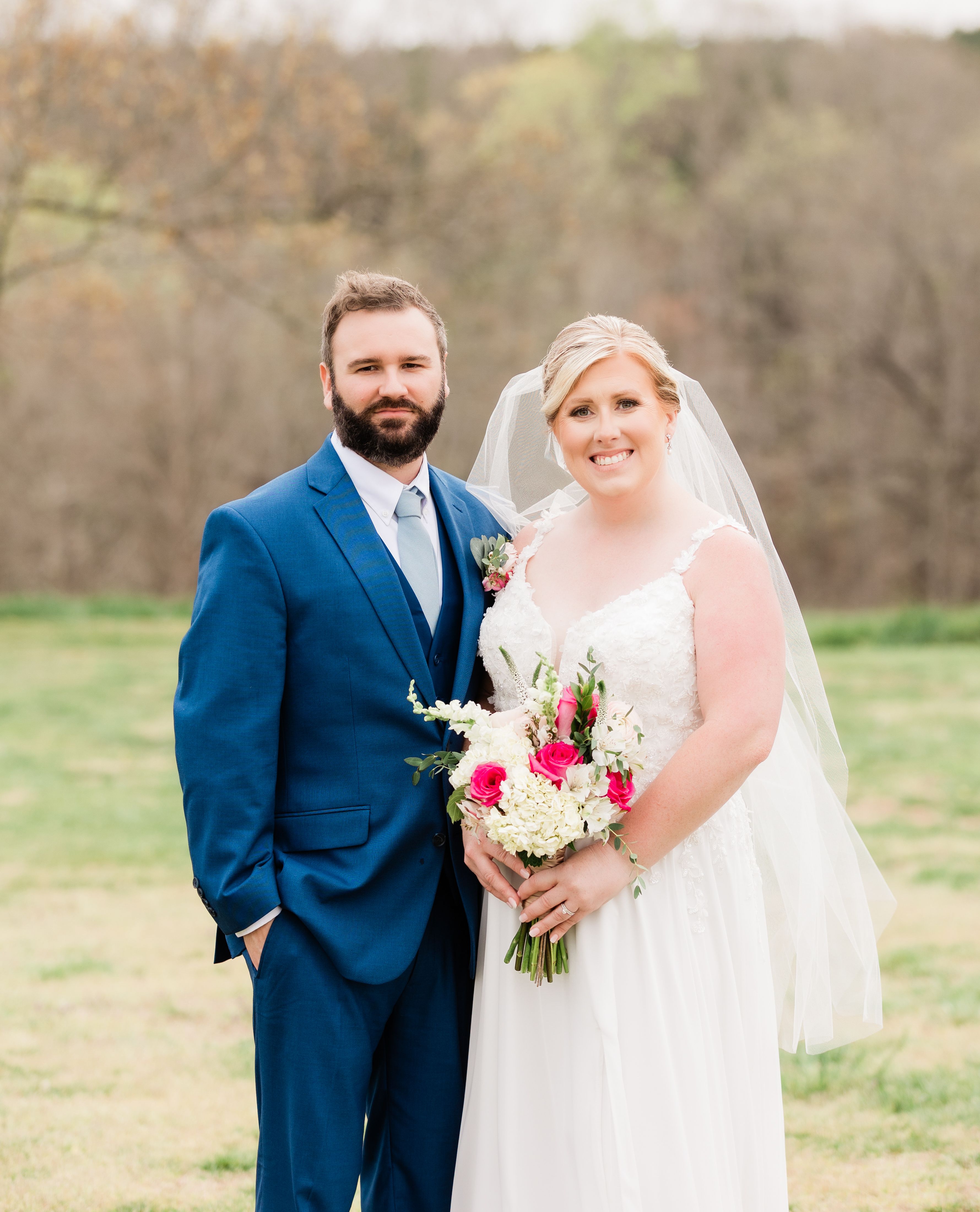 Charming outdoor wedding portrait of a smiling couple in formal attire, set against a natural backdrop.