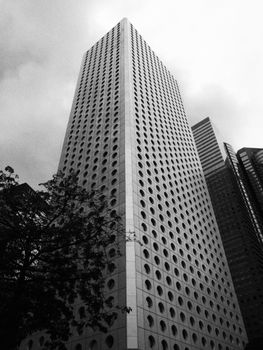 Striking black and white photo of a modern skyscraper with circular windows in an urban setting.