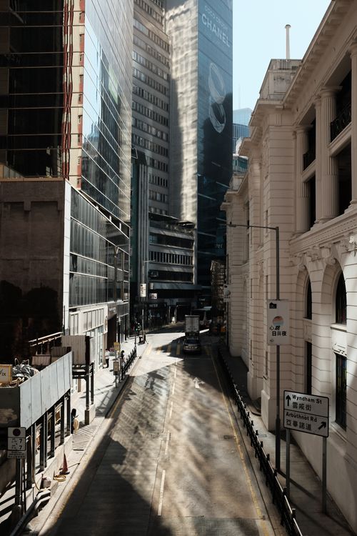 Free High-rise buildings line a quiet urban street, casting reflections and shadows. Stock Photo