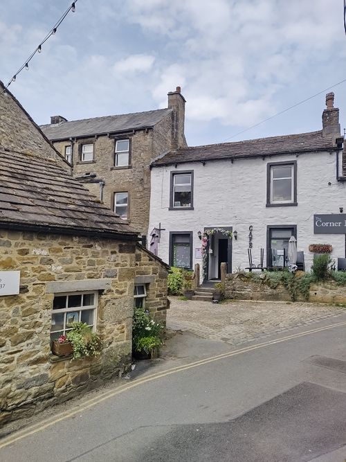 Free Explore the charm of a picturesque village street lined with historic stone buildings under a cloudy summer sky. Stock Photo