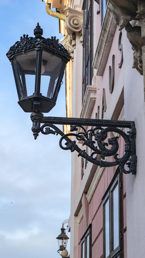 Free Ornate street lantern hanging on a historic building facade with classic architecture. Stock Photo