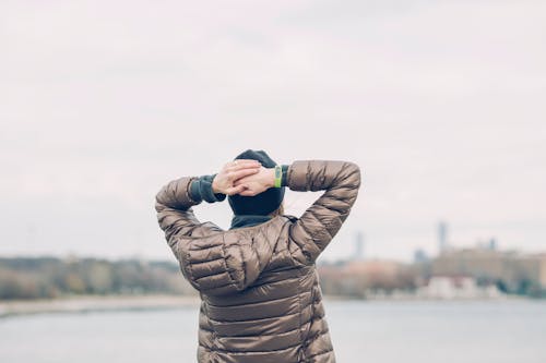 Person Holding Head Facing Body of Water