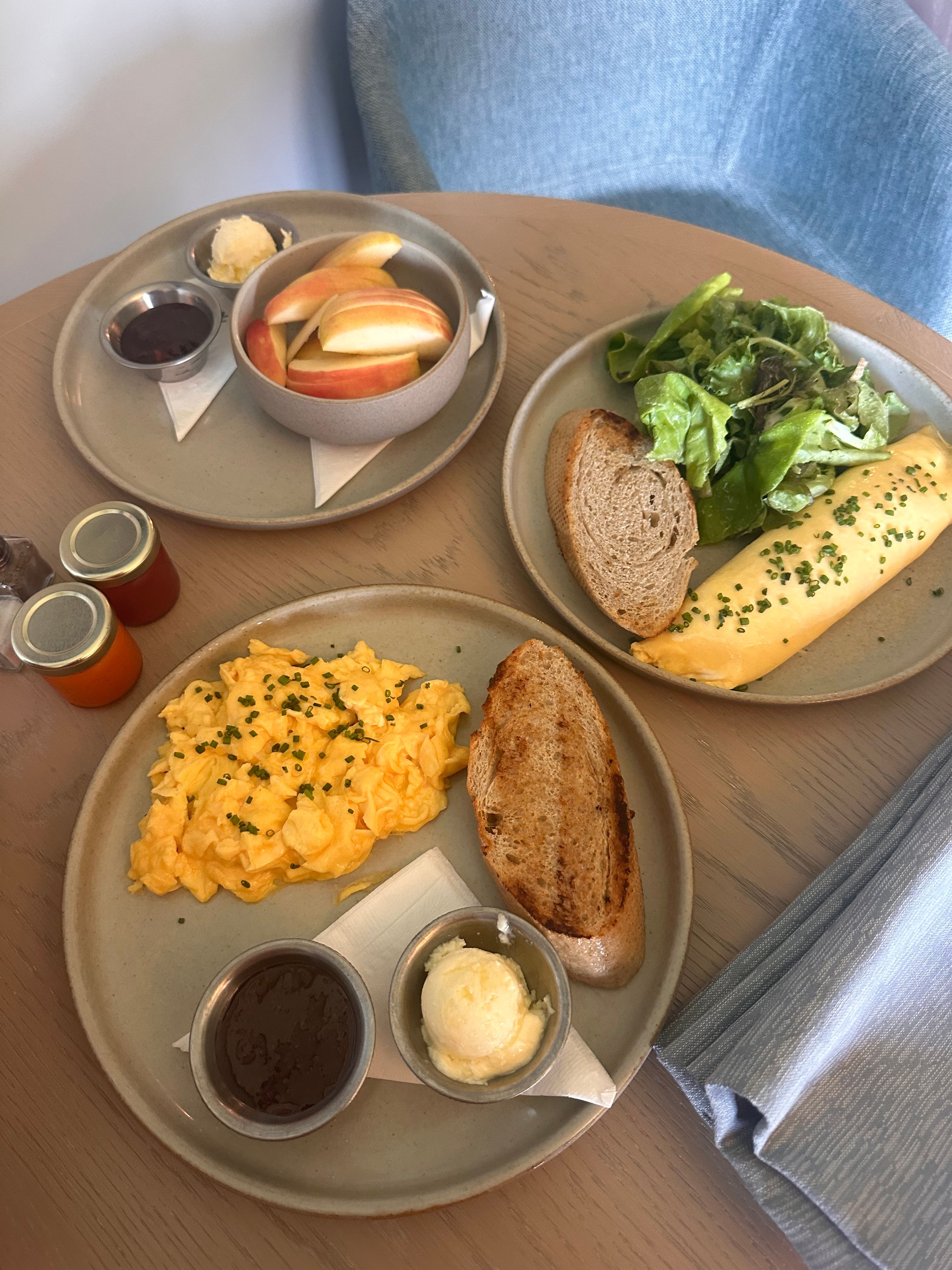 Scrambled eggs, omelette, salad, and toast on a wooden table. Perfect brunch setup.