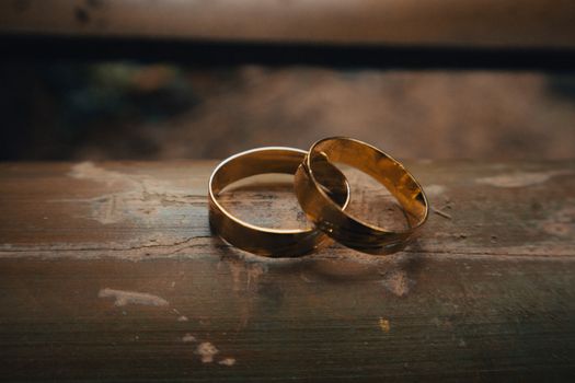 Beautiful gold wedding rings placed elegantly on a rustic wooden surface.