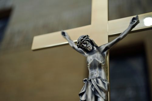 Free A close-up of a sacred silver crucifix on a golden cross indoors, depicting Christian symbolism. Stock Photo